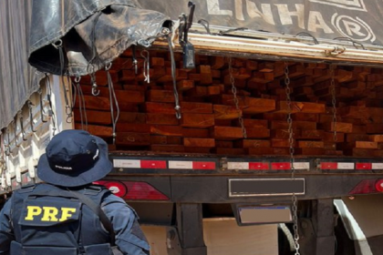 Agente da PRF observa carga apreendida em caminhão